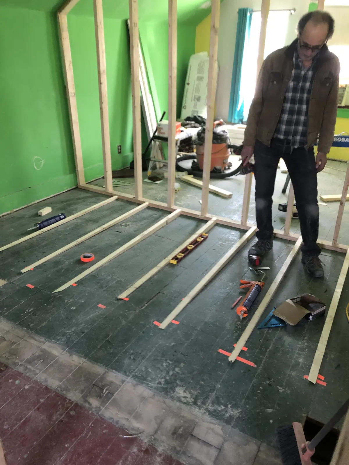 Marking and measuring the second-floor slope before installing leveling shims, 1890s Rogers Park worker's cottage renovation