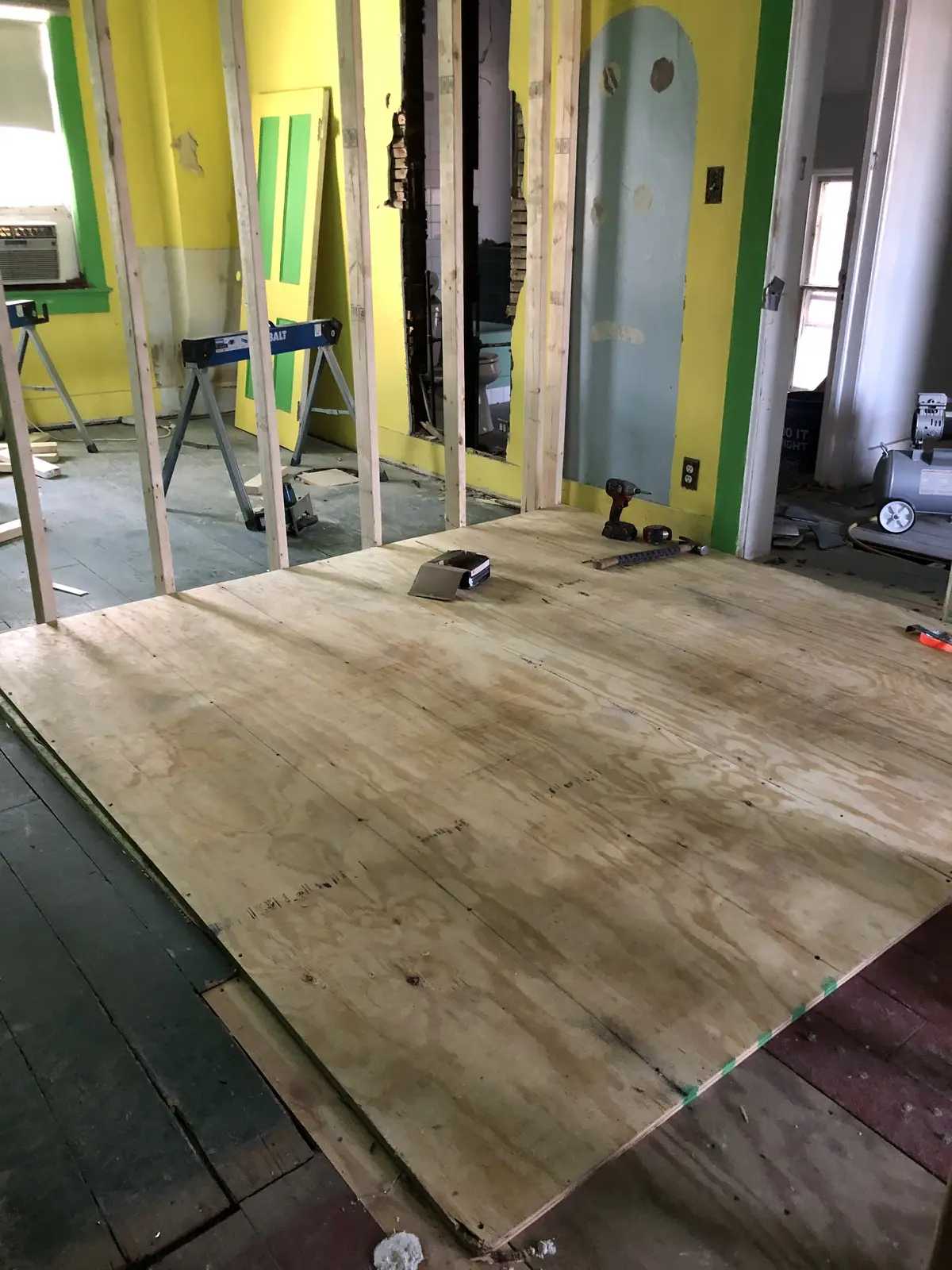 New plywood subfloor installed over tapered leveling shims during a whole-house renovation, Rogers Park